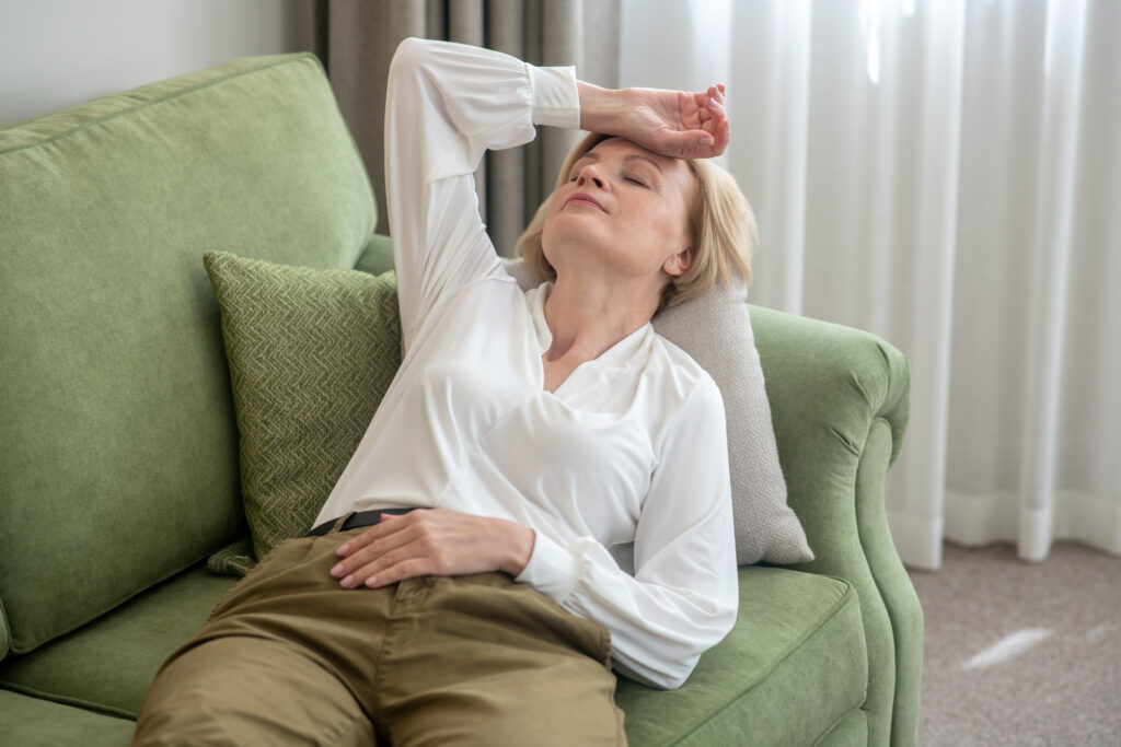 Donna matura distesa sul divano sofferente per il mal di testa
